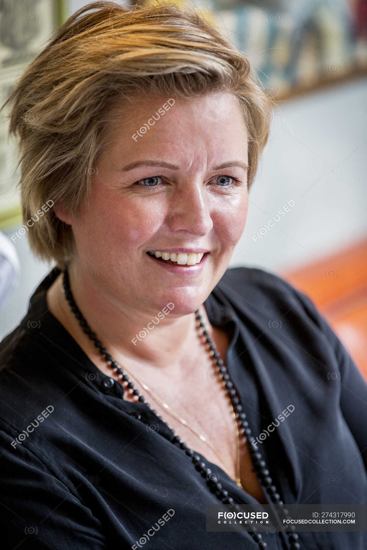 Portrait Of Smiling Mature Woman With Short Blonde Hair In Black