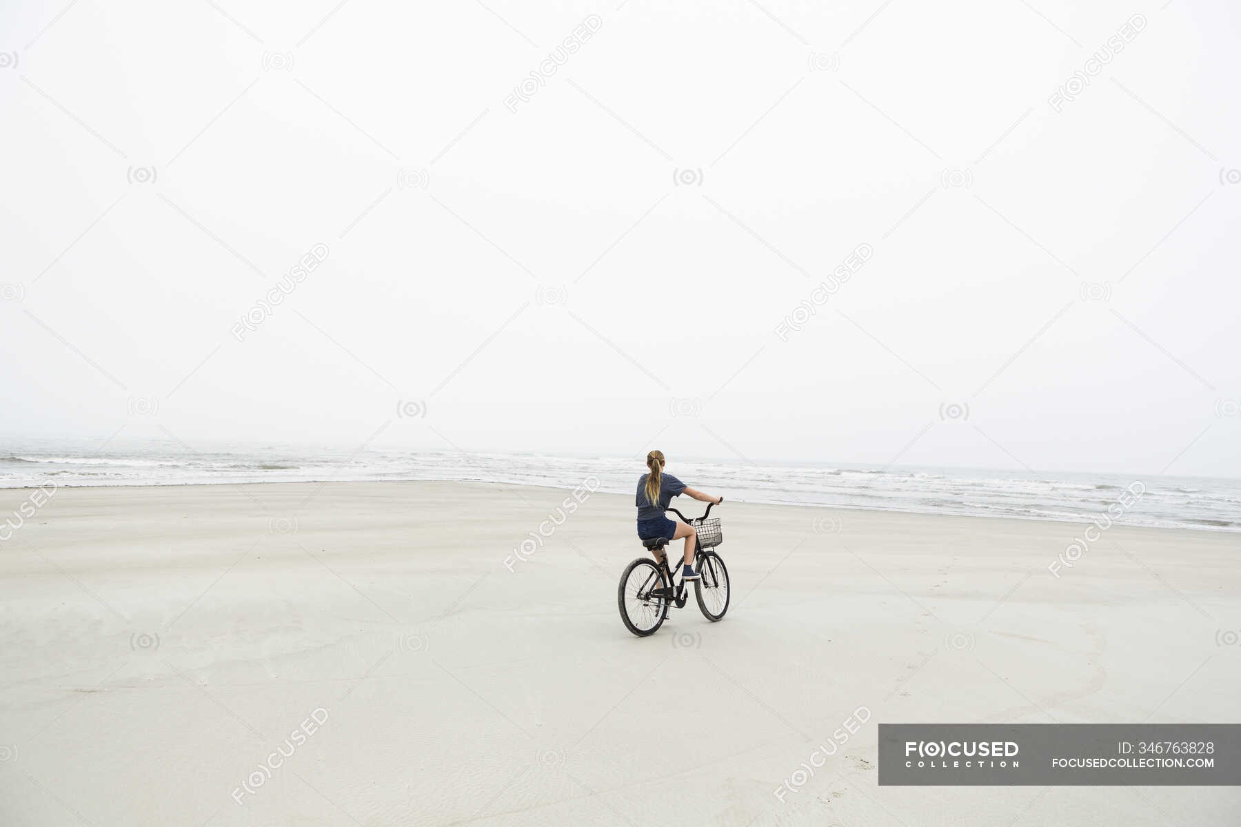 Teen girl biking on sandy beach by the ocean, St. Simons Island, — travel, freedom