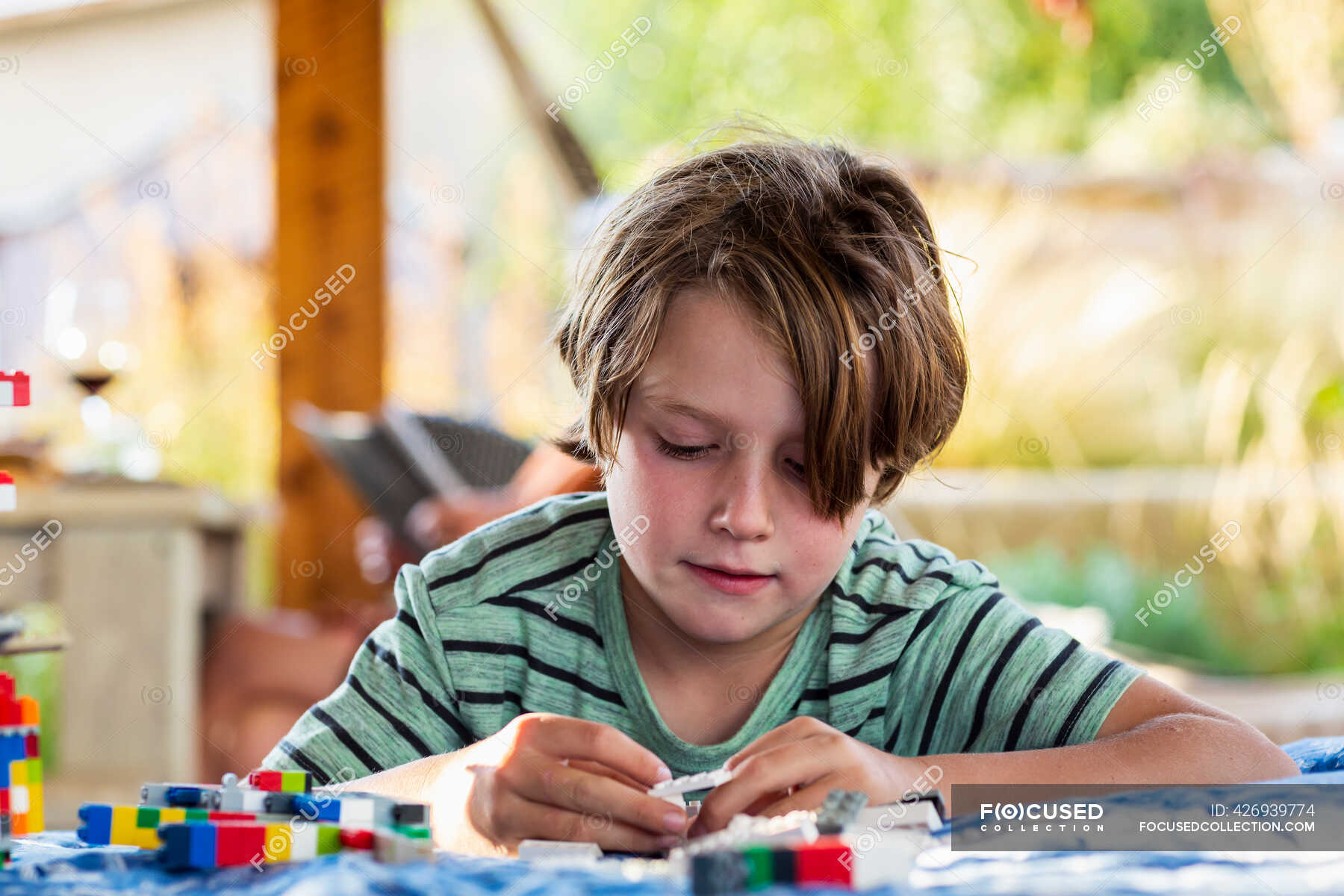 Seven year old boy playing with building blocks on a terrace — Pre Teen ...