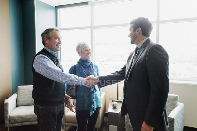 Man greeting a mature couple in an office. — Stock Photo