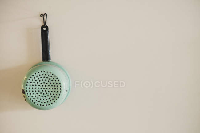 Enamel colander hanging on a wall — Stock Photo