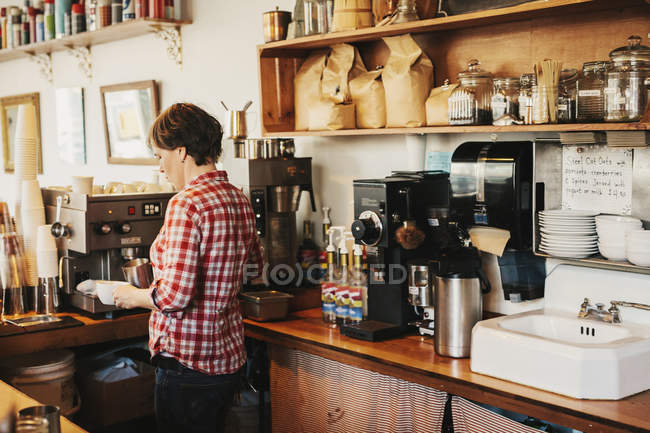 Femme en chemise à carreaux travaillant derrière le comptoir — Photo de stock