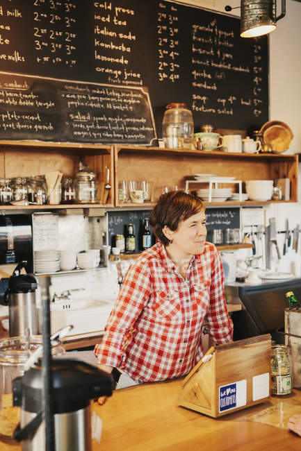 Woman in a plaid shirt working behind the counter — Stock Photo