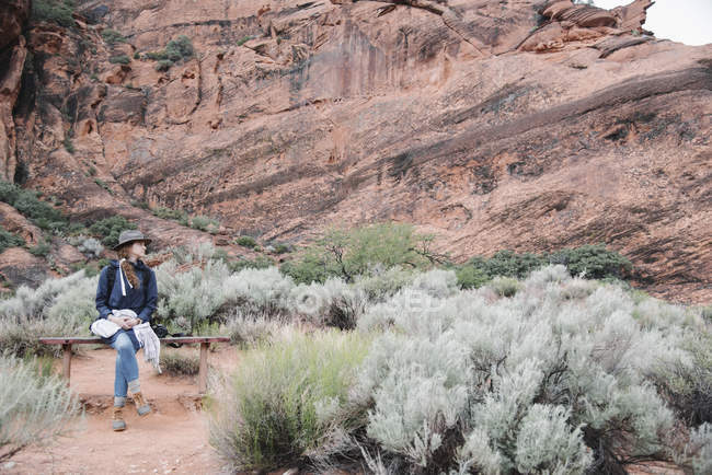 Улыбающаяся женщина сидит на скамейке в каньоне . — стоковое фото