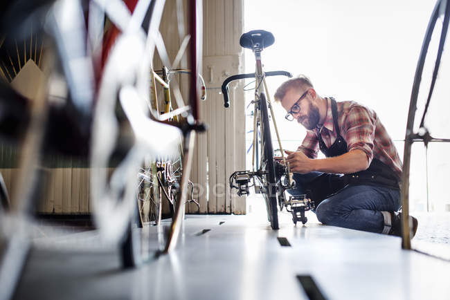 Uomo in officina riparazione biciclette . — Foto stock