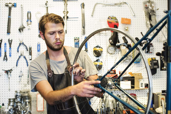 Мужчина ремонтирует велосипедный магазин . — стоковое фото