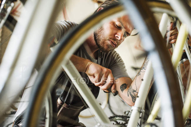Uomo che lavora in un negozio di riparazione di biciclette — Foto stock