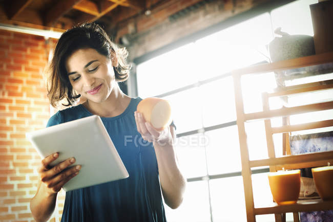 Молодая женщина с цифровым планшетом и ароматной свечой
. — стоковое фото