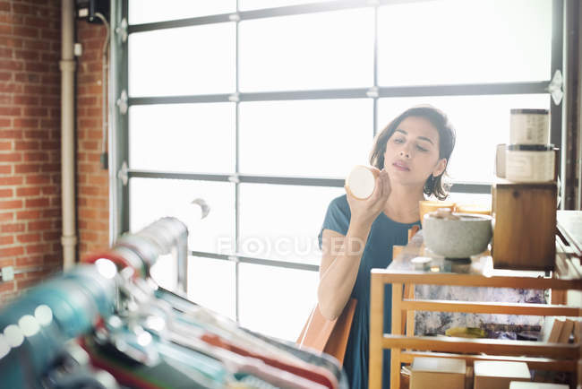 Giovane donna guardando una tazza di ceramica . — Foto stock