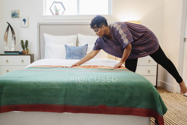Woman smoothing a green fabric quilt — Stock Photo