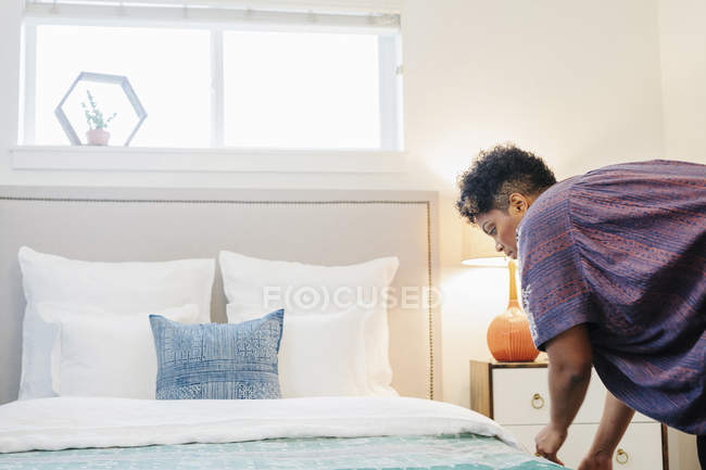 Mulher fazendo uma cama de casal com lençóis — Fotografia de Stock