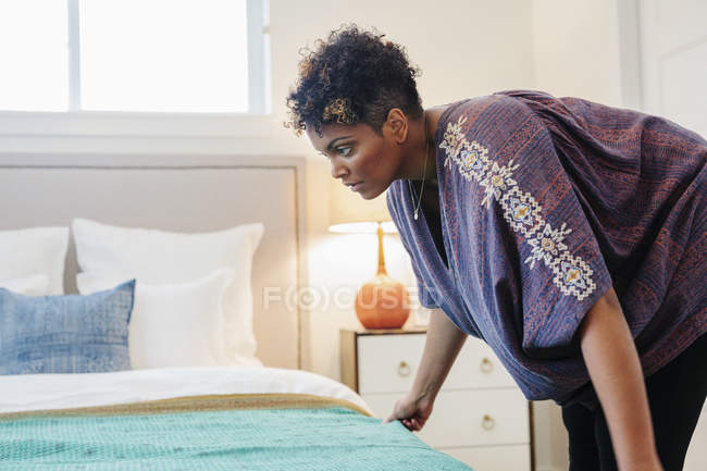 Woman smothing a throw over a double bed — Stock Photo