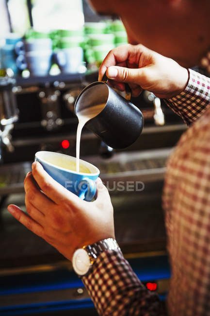 Persona haciendo café y vertiendo leche - foto de stock