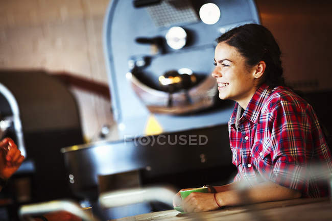 Улыбающаяся женщина, сидящая за стойкой с чашкой кофе — стоковое фото