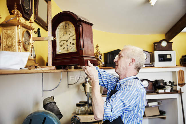 Clockmaker showing a clock — Stock Photo