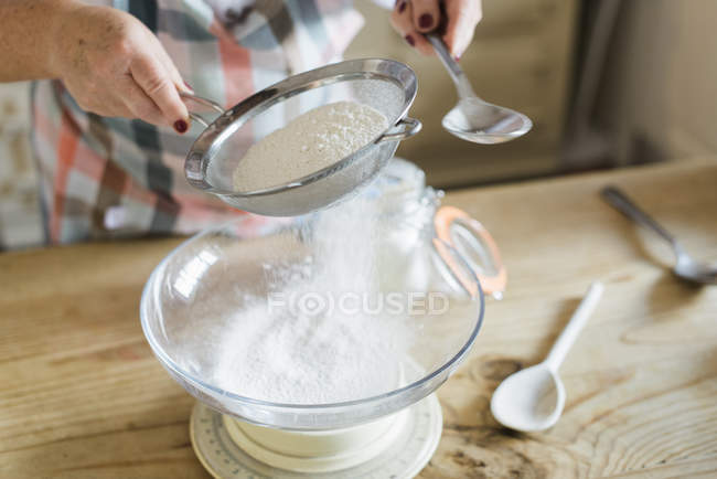 Donna setacciando farina bianca — Foto stock