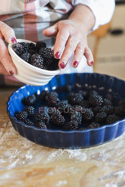 Woman pouring fresh blackberries — Stock Photo
