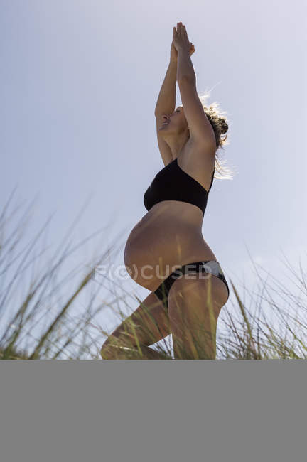 Беременная женщина, стоящая в позе йоги — стоковое фото
