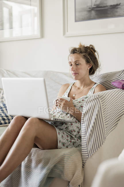 Mujer embarazada usando el ordenador portátil - foto de stock