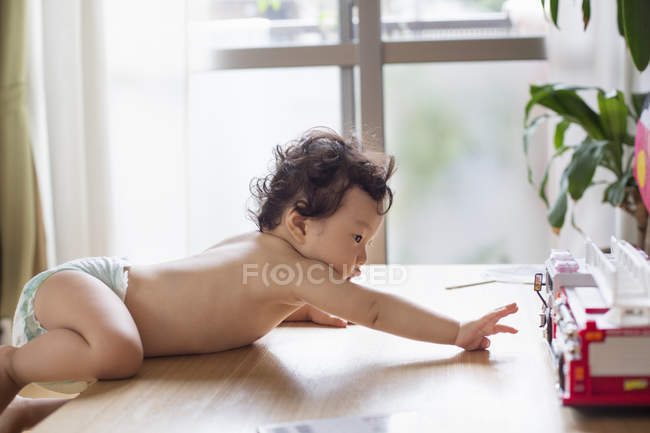 Baby climbing on a table. — Stock Photo