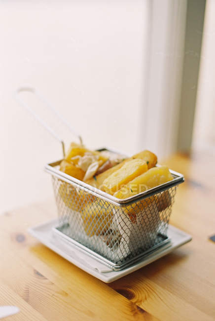 Small wire basket of fried potatoes — Stock Photo
