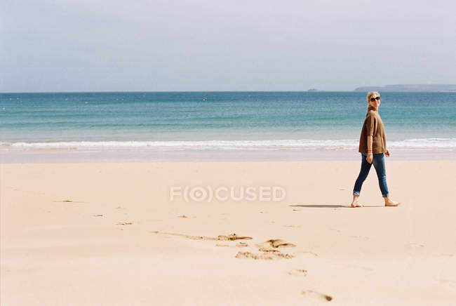Donna che cammina scalza su una spiaggia — Foto stock