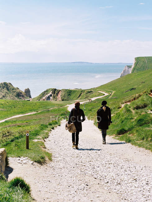 Duas mulheres caminhando em um litoral — Fotografia de Stock