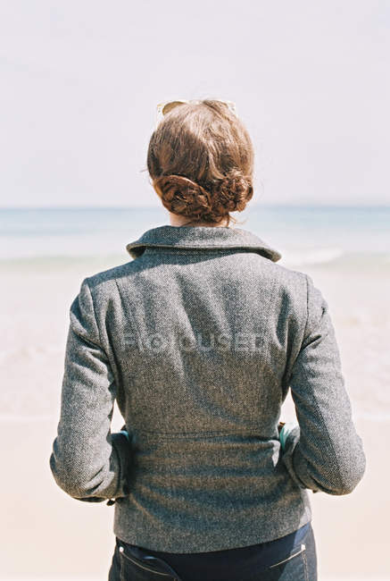 Mujer con una chaqueta gris mirando hacia fuera - foto de stock