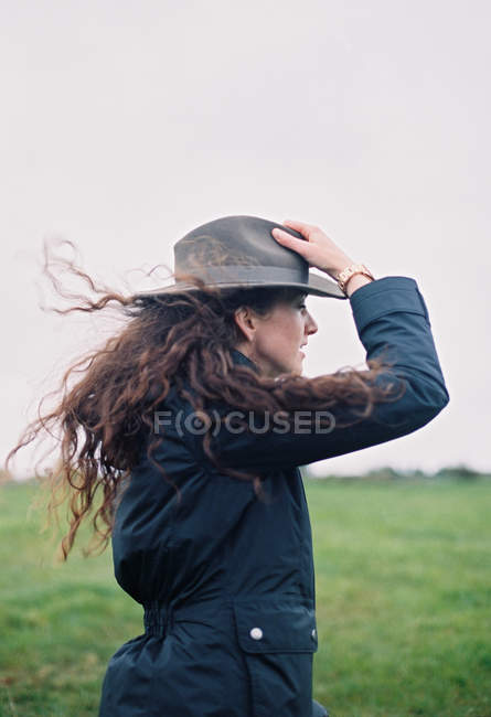 Woman in the breeze holding her hat. — Stock Photo