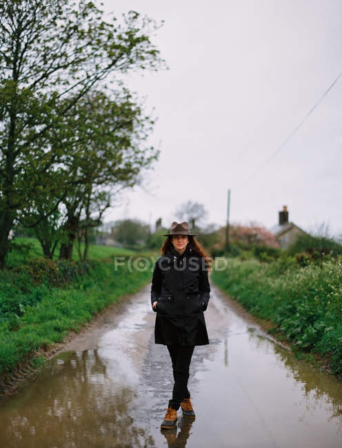 Femme marchant sur une route mouillée — Photo de stock