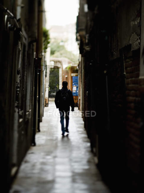 Man walking down a narrow alleyway — Stock Photo