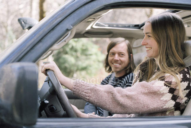 Улыбающаяся молодая пара за рулем автомобиля . — стоковое фото