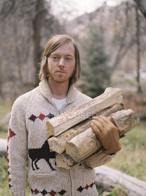 Homme portant du bois de chauffage — Photo de stock