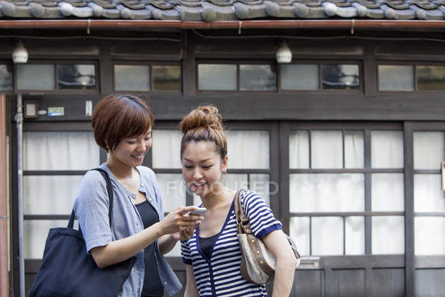Japonais les femmes regardant cellulaire . — Photo de stock
