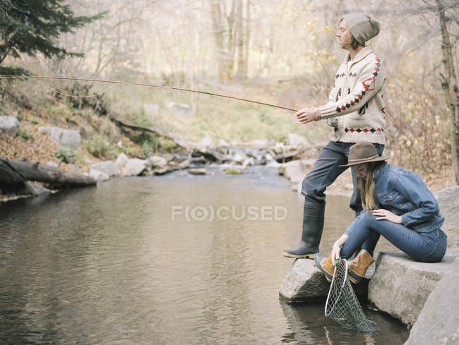 Giovane coppia pesca in un fiume
. — Foto stock