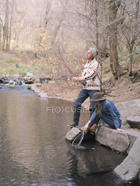Giovane coppia pesca in un fiume . — Foto stock