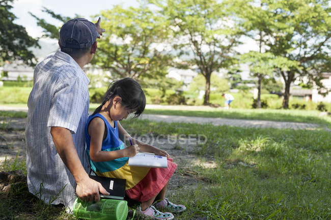 Father and daughter sitting outdoors. — Stock Photo
