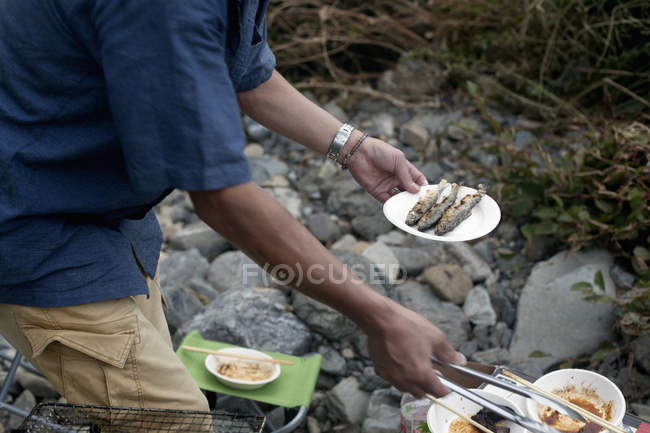 Чоловік тримає тарілку риби на грилі — стокове фото