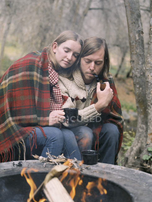 Jeune couple assis près d'un foyer — Photo de stock