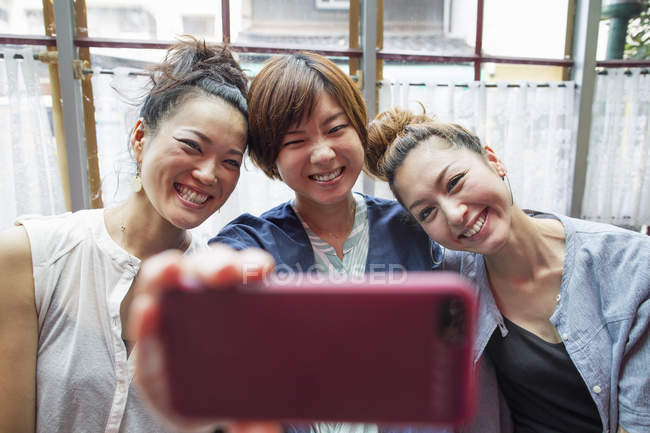 Trois femmes regardant un téléphone portable — Photo de stock