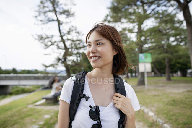 Donna nel parco che porta uno zaino . — Foto stock
