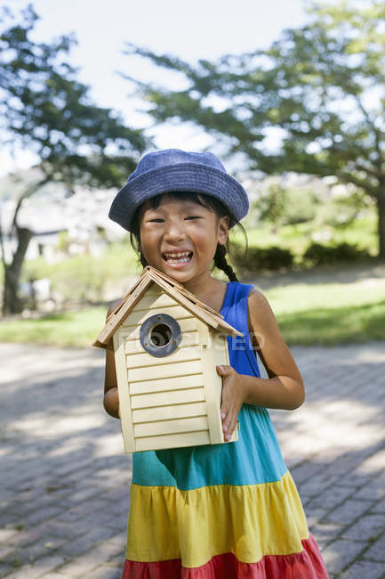 Japanese girl holding a bird house. — Stock Photo