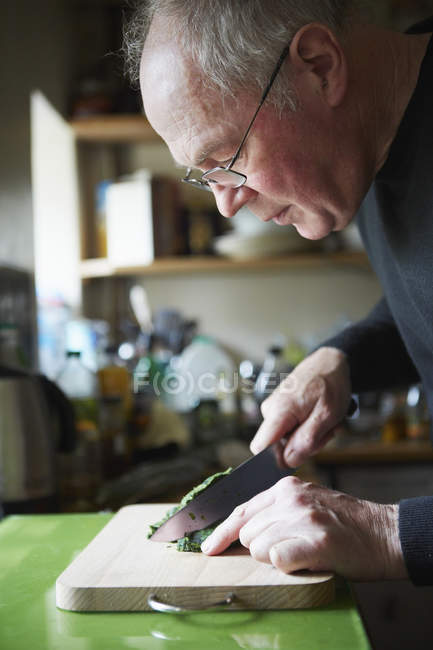 Mature man chopping herbs — Stock Photo