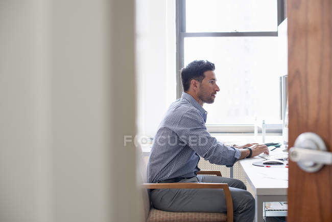 Людина в офісі за допомогою комп'ютера — стокове фото