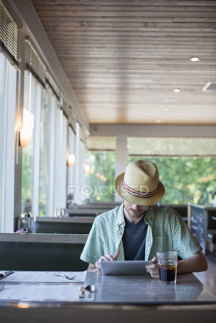 Человек с помощью цифрового планшета сидит в закусочной — стоковое фото
