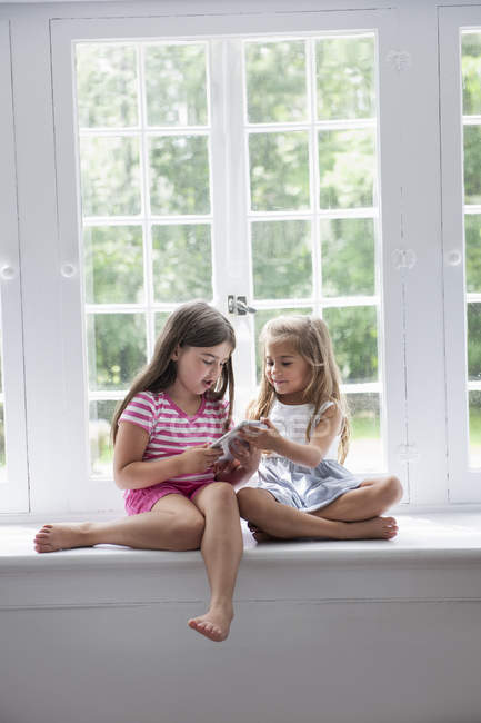 Deux filles jouant avec une tablette numérique — Photo de stock