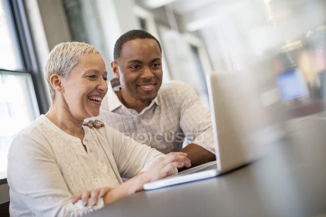 Menschen blicken auf Laptop-Bildschirm und lachen. — Stockfoto