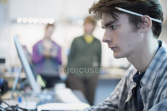 Mann sitzt in einer Werkstatt am Computer. — Stockfoto