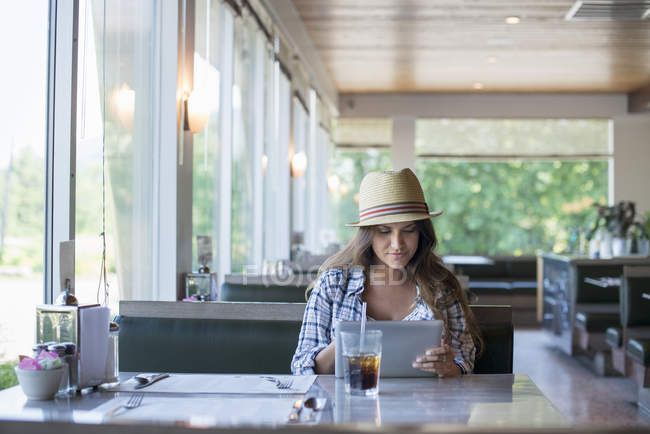 Mujer sentada en una mesa en un restaurante - foto de stock