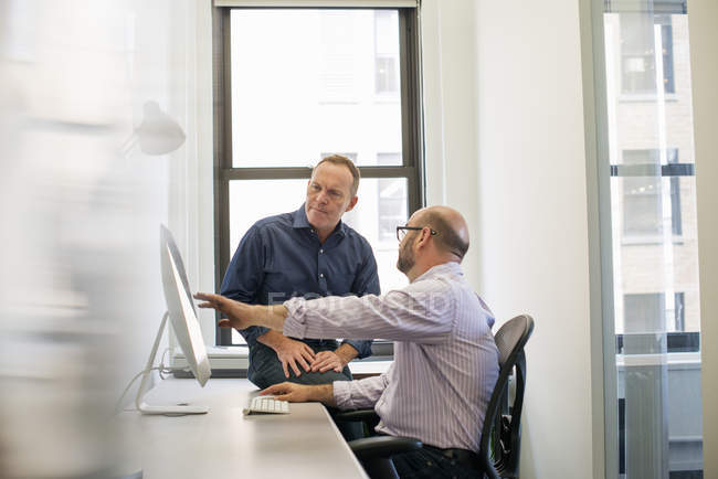 Business colleagues in an office talking and referring — Stock Photo